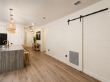 An open-plan interior showing a large white shiplap wall with a black sliding barn door.