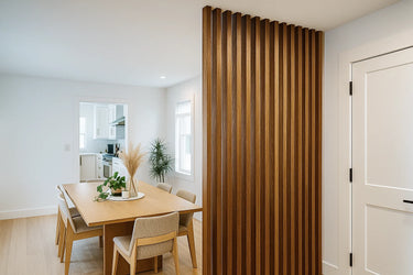 A tall room divider made of evenly spaced walnut wood slats is used to separate open-concept living areas while adding warmth and texture to the space.